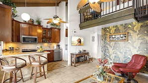 A spacious kitchen with wooden cabinets, a microwave, and a dining area with wicker chairs.