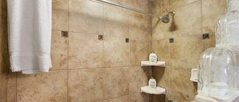 A bathroom with beige tiles, a white towel, and a glass shower enclosure.