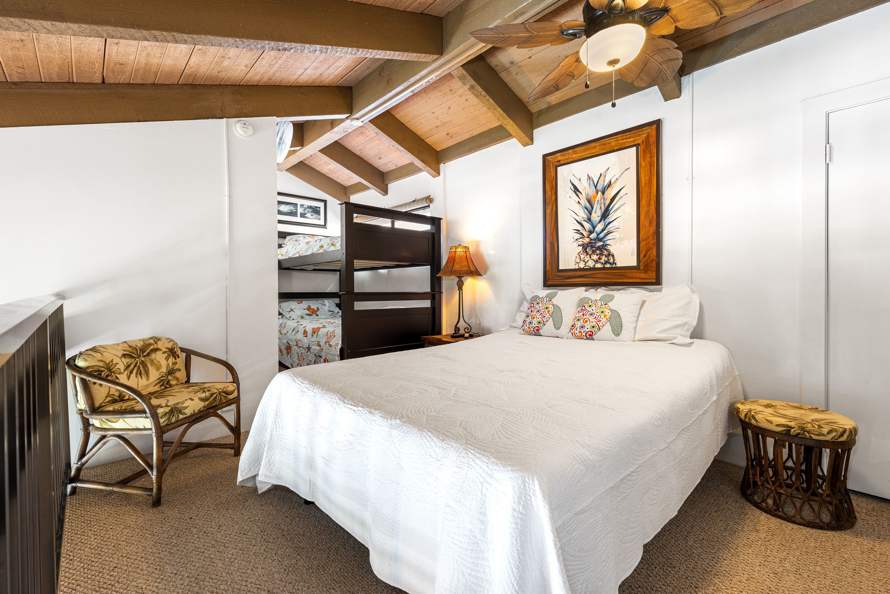 Ein Schlafzimmer mit einem großen Bett, einer Holzbalkendecke, einer Wandlampe und einem gerahmten Bild.