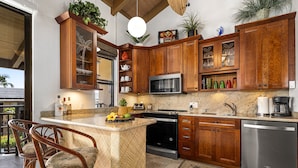 A kitchen with wooden cabinets, a granite countertop, a built-in microwave, and a stainless steel dishwasher.