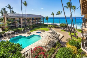 A hotel with a pool, lounge chairs, and a view of the ocean.