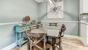 A dining area with a wooden table and chairs, a blue cabinet, and a framed artwork on the wall. -  One block to Beach! Clean, Bright, newly renovated 3BR 2BA Flat  (Fernandina Beach)