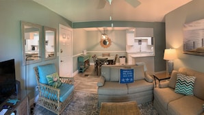 A living room with a sofa, a coffee table, a TV, and a dining area with a table and chairs. -  One block to Beach! Clean, Bright, newly renovated 3BR 2BA Flat  (Fernandina Beach)