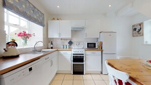 A modern kitchen with white cabinets, a Bosch dishwasher, a stove, a microwave, and a refrigerator. - Pant Glas - 1 Bedroom Cottage, in the countryside (Dwygyfylchi)