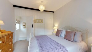 A bedroom with a bed, bedside tables, a dresser, a chandelier, and framed pictures on the wall. - Pant Glas - 1 Bedroom Cottage, in the countryside (Dwygyfylchi)