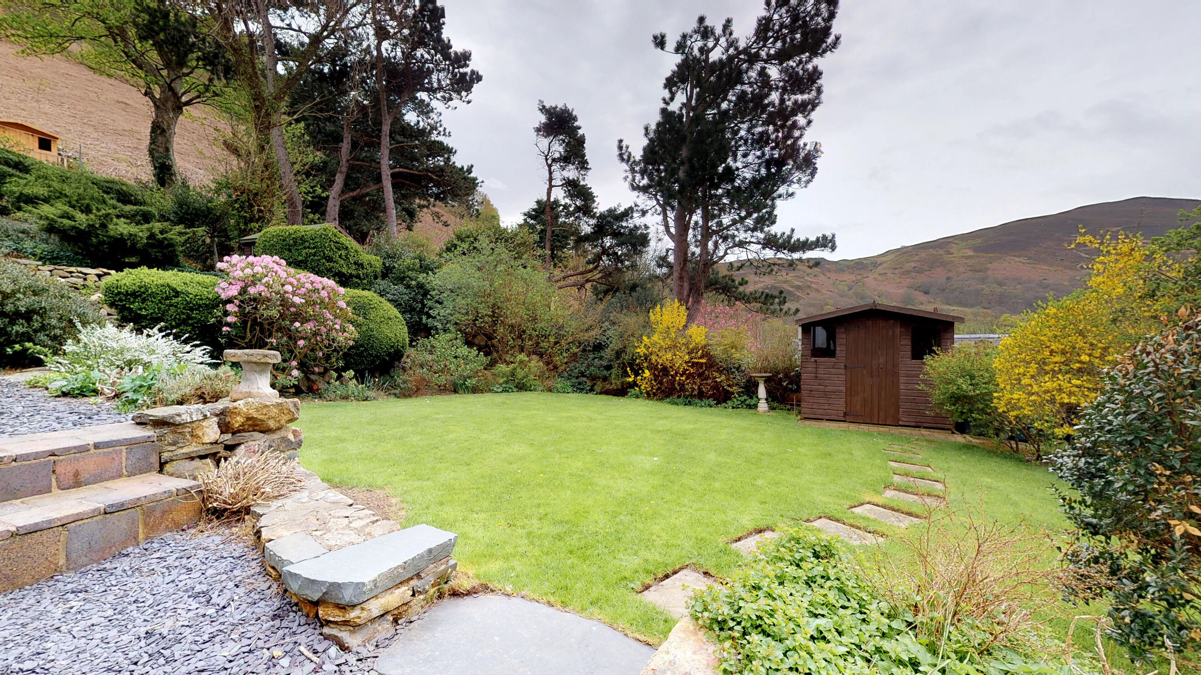A well-maintained garden with a stone pathway leading to a wooden shed.