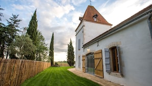 A white building with a red-tiled roof, a wooden fence, and a well-maintained lawn.