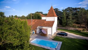 A house with a swimming pool, a covered patio, and a fenced yard.
