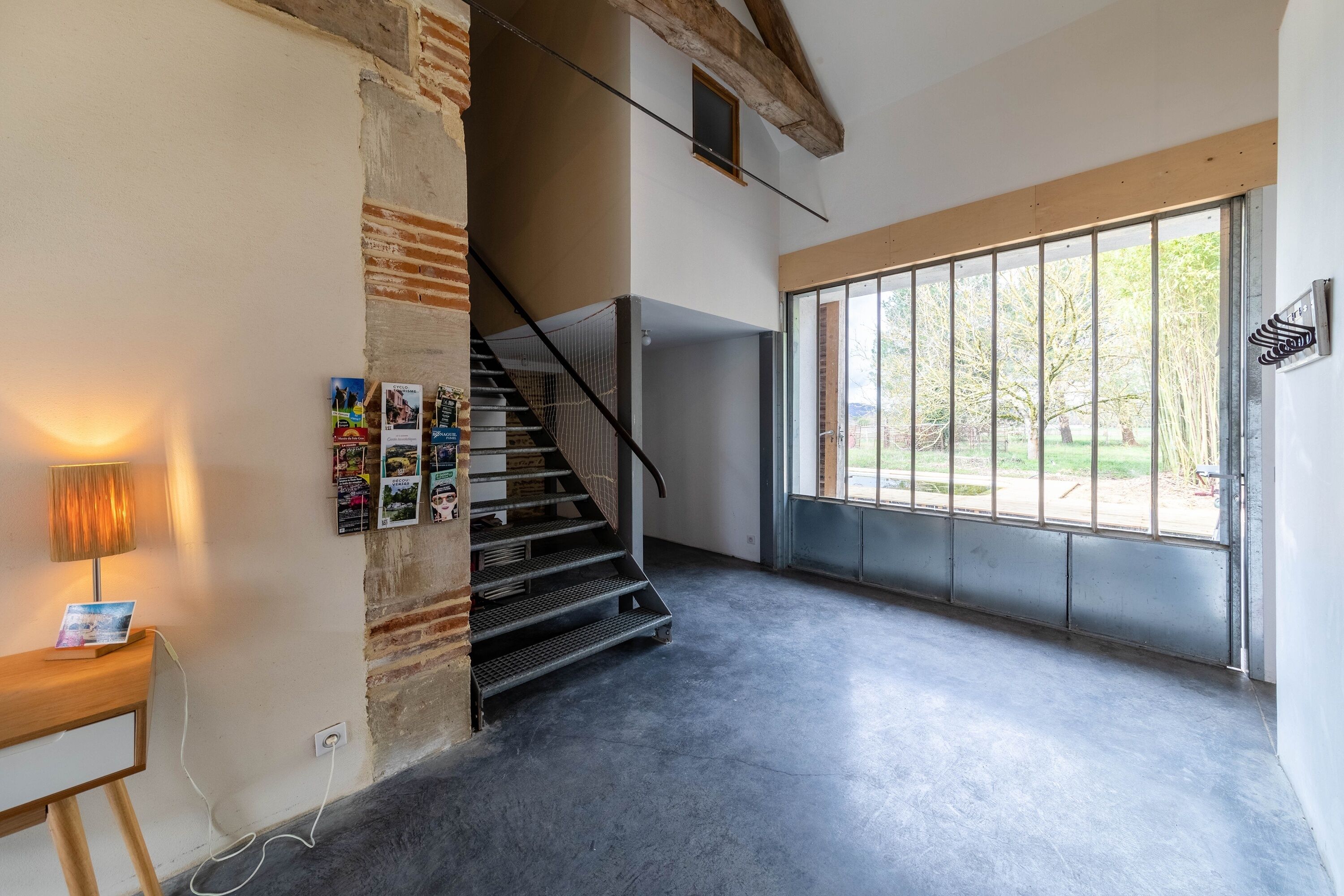 Een modern interieur met een trap, een groot raam en een wandlamp.