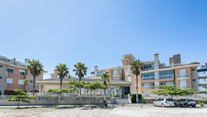 A multi-story residential building with balconies, palm trees, and a parking area. - 350m from the Beach | Pool | Barbecue #IA20 (Florianópolis)