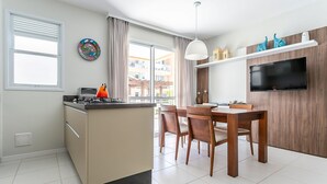 A modern kitchen with a central island, dining table, and chairs. There is a built-in oven, a microwave, and a stove. - 350m from the Beach | Pool | Barbecue #IA20 (Florianópolis)