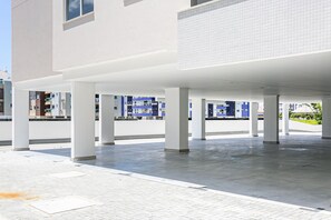 A spacious covered outdoor area with a tiled floor and concrete pillars.