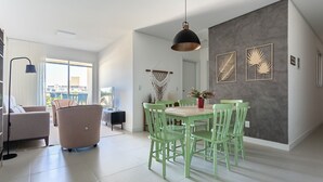 Un salon moderne comprenant un coin repas, une grande fenêtre et un mur d’accent de couleur grise.