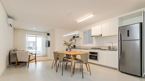 A modern kitchen with a dining area, stainless steel appliances, and a large window.