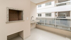 A modern apartment with a kitchen area, a built-in brick fireplace, and a balcony with a glass railing.