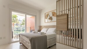 A bedroom with a bed, a sliding glass door to a balcony, and a wooden partition. - Gastronomy | 120m from the Beach | Pool #CAMP07 (Florianópolis)