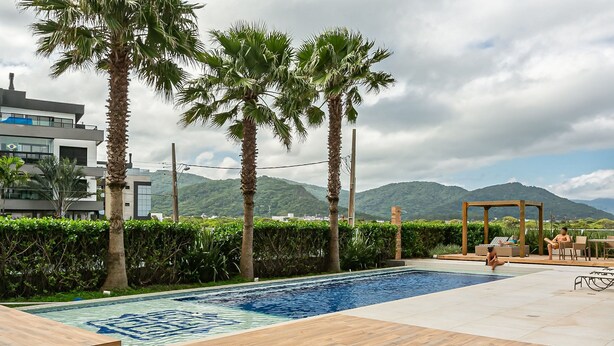 A swimming pool with wooden deck, palm trees, and a mountain view. - Gastronomy | 120m from the Beach | Pool #CAMP07 (Florianópolis)