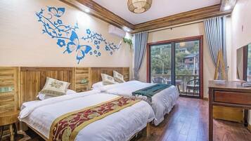 Une chambre d’hôtel avec deux lits, une tête de lit en bois, une grande fenêtre et un bureau.