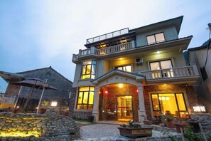 A two-story building with a balcony, large windows, and a well-lit entrance. - Moganshan Yishang Inn (Deqing)