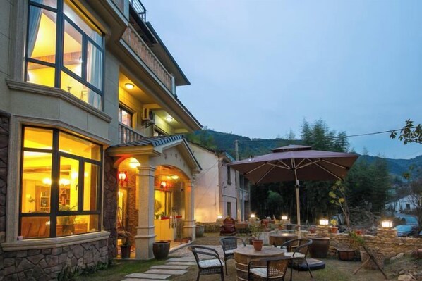 A building with outdoor seating and a large umbrella. - Moganshan Yishang Inn (Deqing)