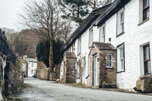 Eine enge Straße gesäumt von traditionellen Steinhäusern und weiß getünchten Gebäuden, was auf eine historische oder ländliche Umgebung hindeutet.
