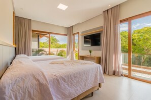 Ein modernes Schlafzimmer mit zwei Betten, einem Fernseher und großen Fenstern mit Blick auf Grünflächen.