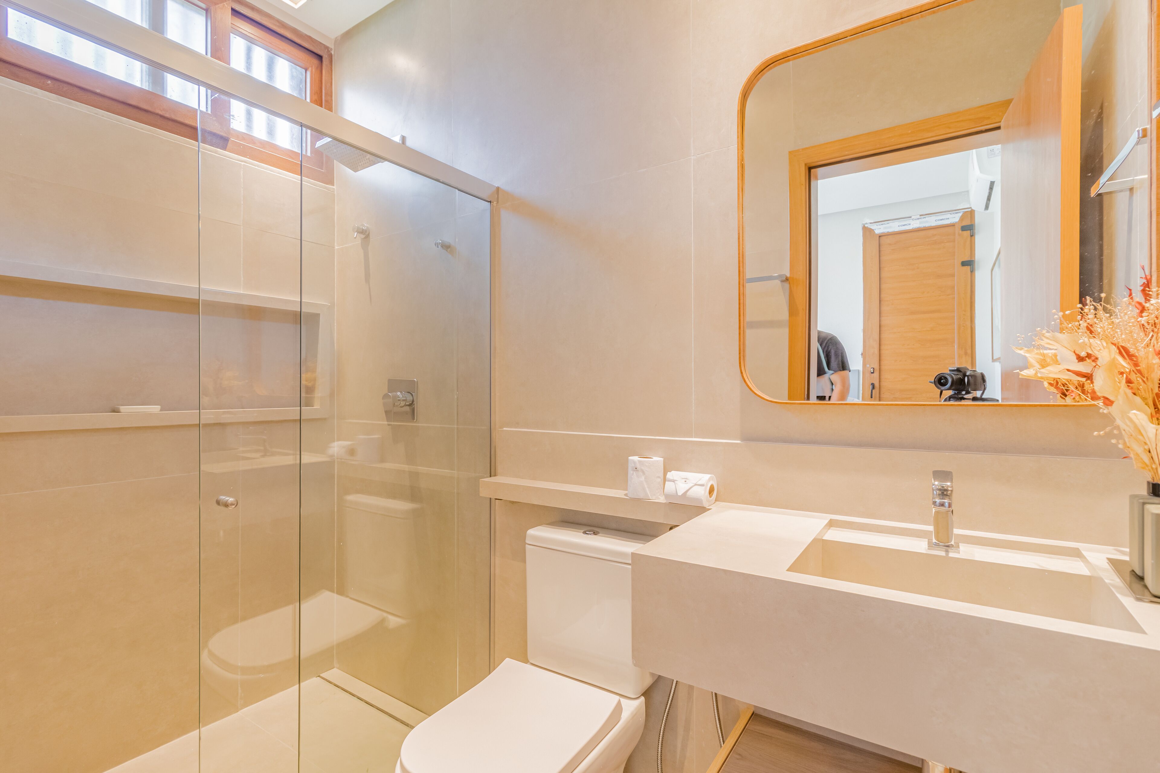 Un baño moderno con ducha de vidrio, inodoro y lavamanos con espejo.