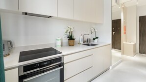 A modern kitchen with white cabinetry, a built-in oven, and a stainless steel sink.