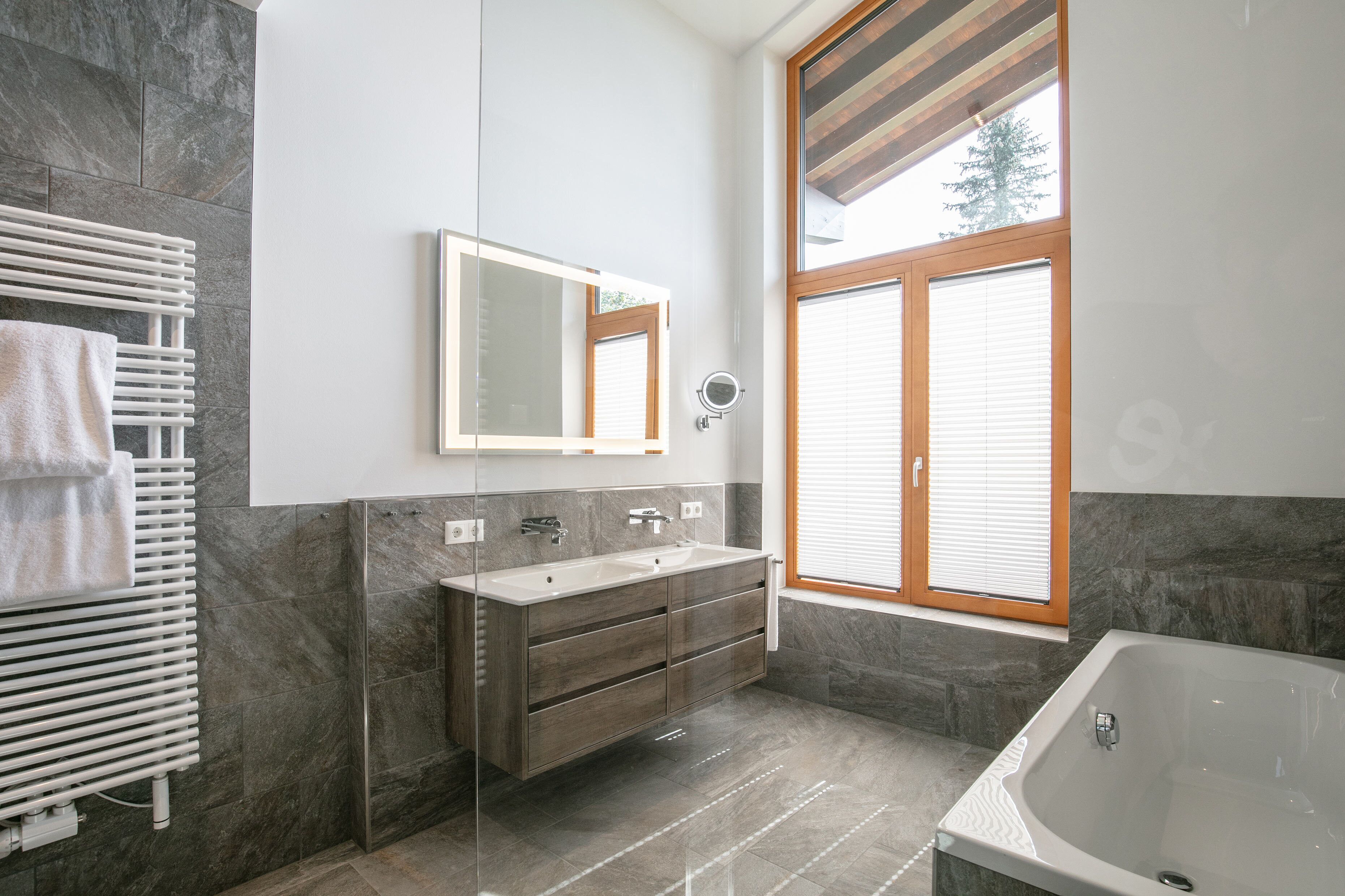 A modern bathroom with a large window, a double sink vanity, and a bathtub.