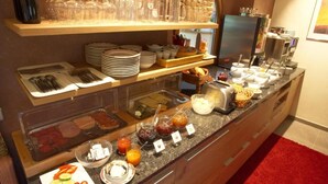 A buffet setup with various food items, utensils, and glassware. - Appart Hotel Amadeus  (Sankt Johann in Tirol)