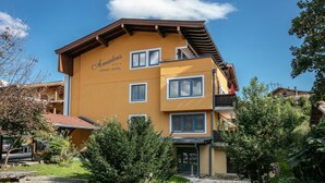 A two-story hotel with a yellow facade and a brown roof. - Appart Hotel Amadeus  (Sankt Johann in Tirol)
