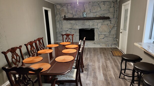 Un comedor con pared de piedra, chimenea y ventilador de techo.