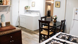 Une cuisine équipée d’une cuisinière, d’un lave-linge et d’une table à manger avec des chaises.