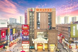 Un edificio de varios pisos con un letrero llamativo en la parte superior, rodeado de otros edificios comerciales y calles concurridas.