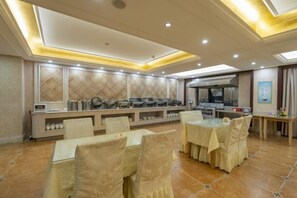 A hotel dining area with a buffet setup, multiple tables, and chairs.