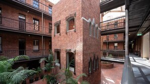 Un patio con edificios de ladrillo, plantas en macetas y un corredor cubierto.