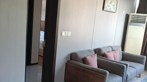 Un salon moderne avec un canapé gris, une table basse en bois et un climatiseur fixé au mur.
