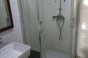 Un baño con ducha de vidrio, un lavabo blanco y un espejo.