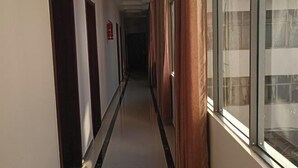 Un couloir avec des portes d’un côté et une fenêtre de l’autre.