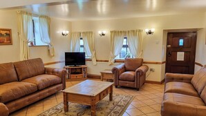 A living room with two brown leather sofas, a wooden coffee table, and a television on a stand. - 3 bedroom accommodation in Onecote (Onecote)