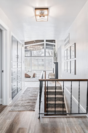 Stairs lead to an upper level, with a ceiling light and window providing ample illumination.