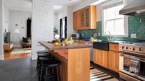 Una cocina moderna con armarios de madera, una isla central con taburetes, una estufa y un microondas.