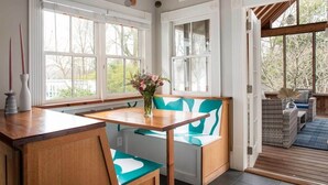 Una cocina con una mesa y banco de madera, ventanas amplias y vistas al exterior.