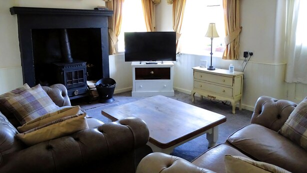 A living room with a fireplace, leather sofas, a television, and a small table. - 2 bedroom accommodation in Thornton Steward, near Leyburn (Thornton Steward, near Leyburn)