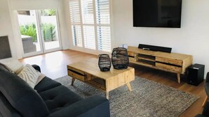 Un salon avec un canapé, une table basse, un téléviseur et des haut-parleurs.