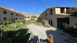 Un cortile con un vialetto sterrato, circondato da edifici con tetti in tegole rosse e pareti color crema.
