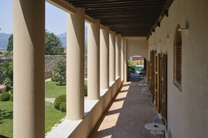 Un couloir extérieur couvert, doté de colonnes, d’un sol en briques et d’un espace aménagé pour s’asseoir.