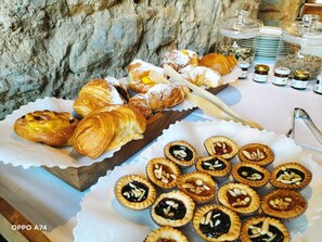 Une variété de viennoiseries et de desserts sont disposés sur une table, notamment des croissants, des tartes et d’autres produits de boulangerie.