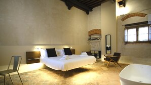 Une chambre avec un grand lit, une chaise, une baignoire et un miroir.