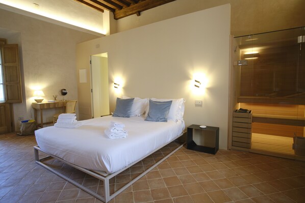 A modern bedroom with a bed, bedside tables, and a built-in bench. - Badia Giulia Prestigious Historical B&B (Camaiore)